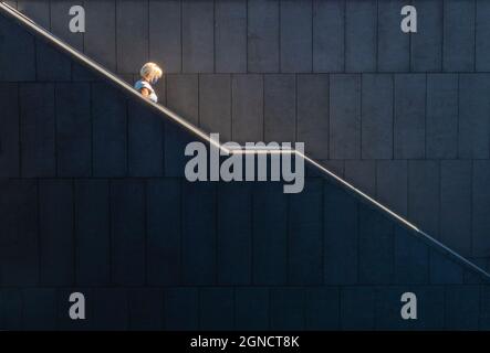 Une femme blonde escaladant les marches d'un grand escalier d'un bâtiment d'architecture contemporaine à Madrid. Banque D'Images