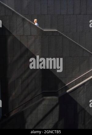 Une femme blonde escaladant les marches d'un grand escalier d'un bâtiment d'architecture contemporaine à Madrid. Banque D'Images