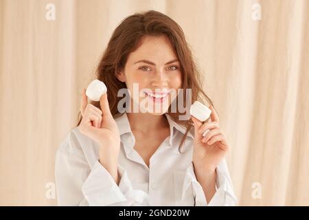 bonne jeune femme avec deux pots de crème dans ses mains sur fond clair Banque D'Images