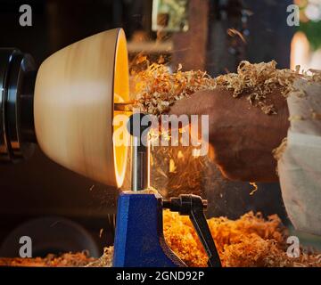 Un bol en bois étant tourné par un homme sur un tour de tourneurs.Un artisan au travail.Sawdust vole. Banque D'Images