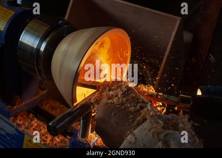 Un bol en bois étant tourné par un homme sur un tour de tourneurs.Un artisan au travail.Sawdust vole. Banque D'Images