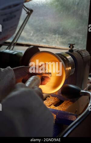 Un bol en bois étant tourné par un homme sur un tour de tourneurs.Un artisan au travail.Sawdust vole. Banque D'Images