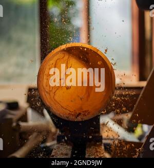 Un bol en bois étant tourné par un homme sur un tour de tourneurs.Un artisan au travail.Sawdust vole. Banque D'Images