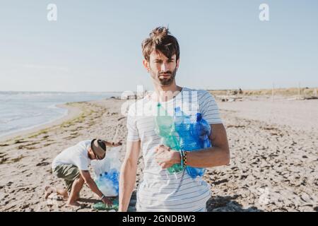 Groupe d'amis activistes collectant des déchets plastiques sur la plage. Les gens nettoyant la plage, avec des sacs. Concept de conservation de l'environnement et de l'océan Banque D'Images