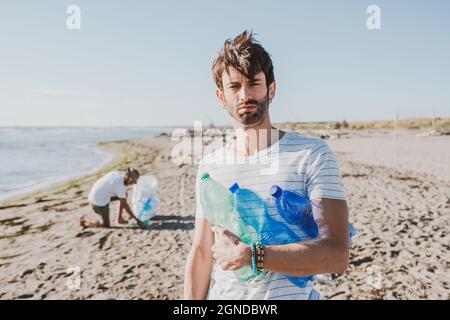 Groupe d'amis activistes collectant des déchets plastiques sur la plage. Les gens nettoyant la plage, avec des sacs. Concept de conservation de l'environnement et de l'océan Banque D'Images