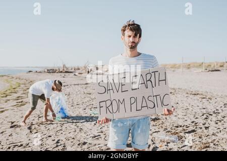 Groupe d'amis activistes collectant des déchets plastiques sur la plage. Les gens nettoyant la plage, avec des sacs. Concept de conservation de l'environnement et de l'océan Banque D'Images