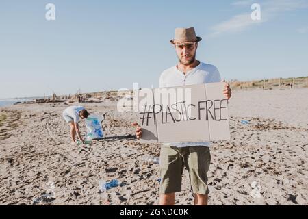 Groupe d'amis activistes collectant des déchets plastiques sur la plage. Les gens nettoyant la plage, avec des sacs. Concept de conservation de l'environnement et de l'océan Banque D'Images