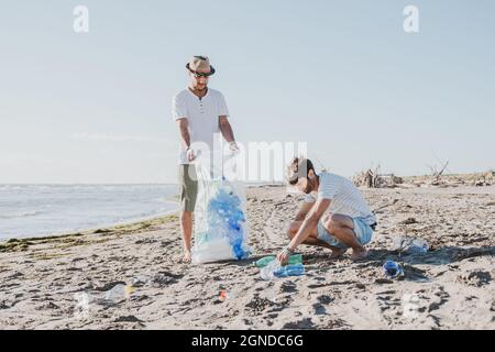 Groupe d'amis activistes collectant des déchets plastiques sur la plage. Les gens nettoyant la plage, avec des sacs. Concept de conservation de l'environnement et de l'océan Banque D'Images