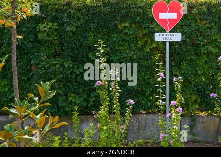 Panneau interdit de passer en forme de coeur dans un parc de Madrid, avec un fond vert et de nombreuses fleurs autour d'un endroit pour mettre le texte qui est le mieux Banque D'Images