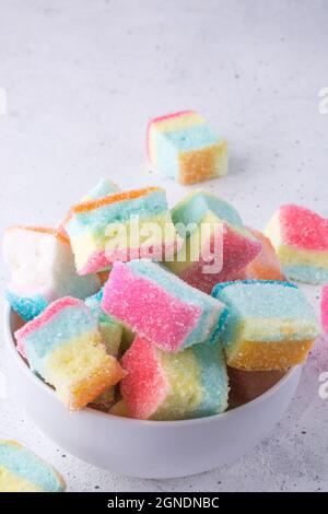 guimauves, confection de sucre doux colorée dans un bol, vue rapprochée de bonbons en forme de cube dispersés sur un fond blanc Banque D'Images