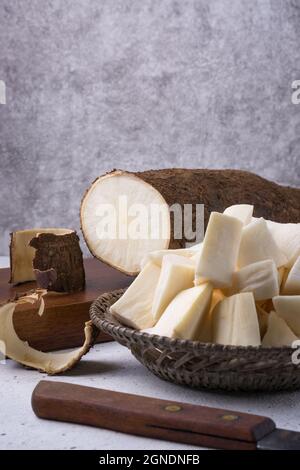 manioc ou manihot, également connu sous le nom de manioc, yuca ou arrowroot brésilien, légumes racines coupés en morceaux prêts à cuire avec une demi-racine coupée, côté vi Banque D'Images