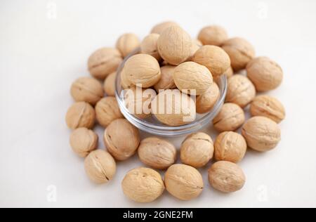 Beaucoup de noix entières dans une tasse sur fond blanc gros plan. Alimentation saine et biologique à haute teneur en protéines. Banque D'Images