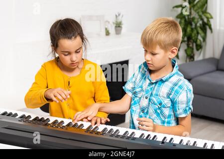 Leçon de musique pour les enfants sur le piano. L'idée d'activités pour l'enfant à la maison pendant la quarantaine. Concept de musique Banque D'Images