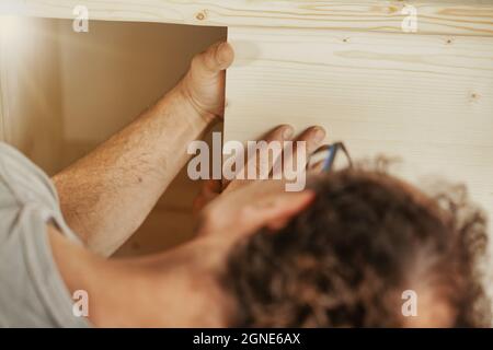 Menuisier ou menuisier faisant une armoire en bois dans un atelier dans un sur l'épaule voew à ses mains en montant un panneau en bois Banque D'Images