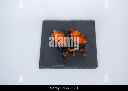 Gunkan Maki avec caviar de saumon servi sur plateau noir isolé sur fond blanc. Cuisine traditionnelle japonaise. Photo de haute qualité Banque D'Images