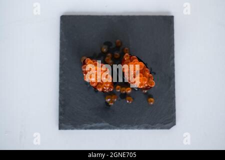 Gunkan Maki avec caviar de saumon servi sur plateau noir isolé sur fond blanc. Cuisine traditionnelle japonaise. Photo de haute qualité Banque D'Images