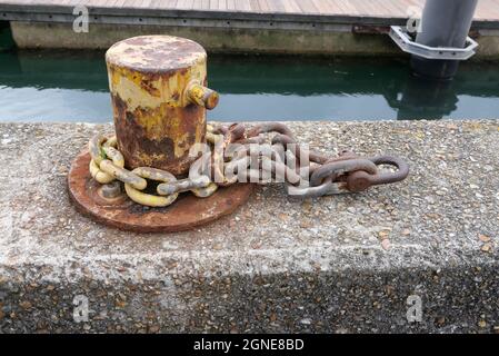 Bollard d'amarrage avec chaîne attachée sur le mur du quai du port Banque D'Images