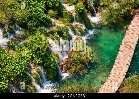 Matinée aérienne avec le parc national de Plitvice. Scène printanière colorée de turistes marchant sur le pont dans une forêt verte avec des lacs et des cascades. Super Banque D'Images