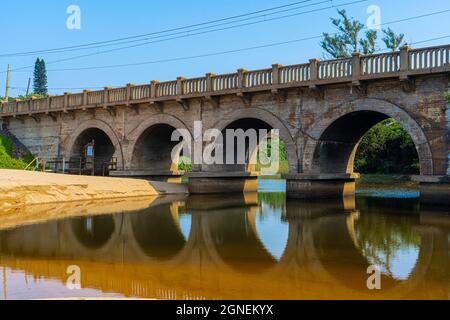 Vieux pont de chemin de fer sur une rivière avec réflexion dans l'eau sur la côte de Durban. Photo de haute qualité Banque D'Images