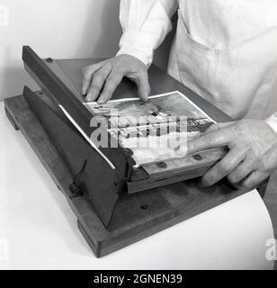 Années 1950, historique, utilisant un coupe-photo en bois pour découper un imprimé noir et blanc produit à partir d'un négatif de film d'appareil photo, Angleterre, Royaume-Uni. Banque D'Images