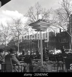 Années 1950, historique, deux hommes, un dans un chapeau, assis à l'extérieur d'un café sur les champs-Elysées, Paris, France, une célèbre avenue de la ville qui passe entre la place de la Concorde et la place Charles de Gaulle, où se trouve l'Arc de Triomphe. Banque D'Images