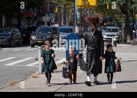 Un juif hassidique portant un shtreimel marche sur Lee Avenue avec 3 enfants. I Williamsburg, Brooklyn, New York. Banque D'Images