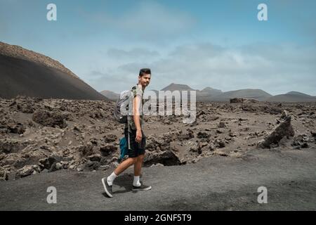 Un jeune homme marche le long d'un chemin à Masdache avec le volcan 'cuervo' en arrière-plan.Lanzarote.Îles Canaries Banque D'Images