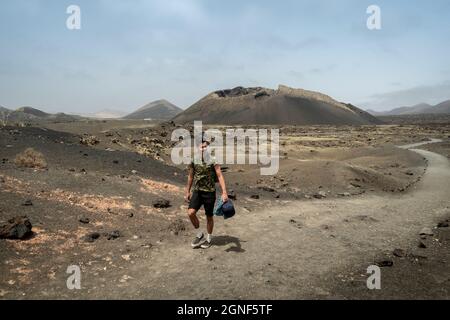 Un jeune homme marche le long d'un chemin à Masdache avec le volcan 'cuervo' en arrière-plan.Lanzarote.Îles Canaries Banque D'Images