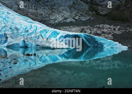 Le glacier bleu de Briksdal, léchant et caressant la mer à sa fin et doublant se reflète dans l'eau de mer, Oban, Norvège Banque D'Images