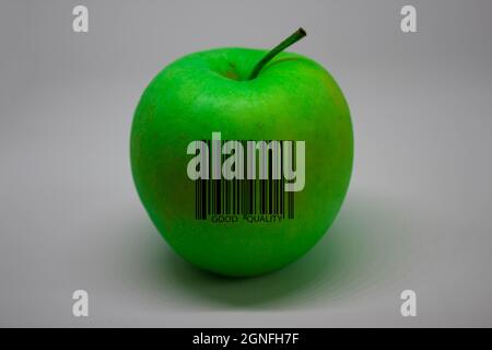 Une pomme verte avec un code-barres indiquant UNE BONNE QUALITÉ sur fond blanc. Banque D'Images