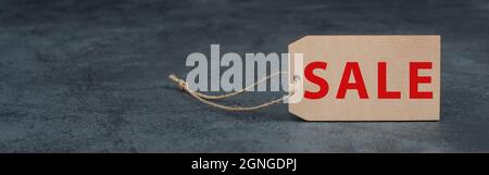 Étiquette en bois avec le mot vente en rouge, fond texturé foncé, espace de copie vide Banque D'Images