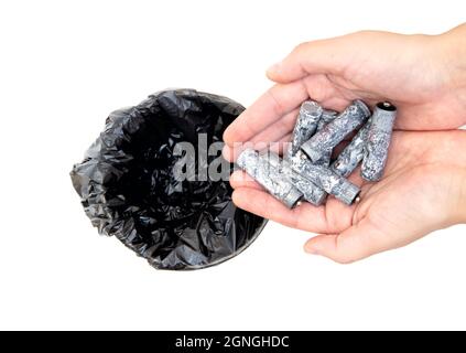 Gros plan des mains des femmes mettant un tas de piles usagées corrodées dans une poubelle isolée sur blanc. Concept de recyclage approprié des batteries. Banque D'Images