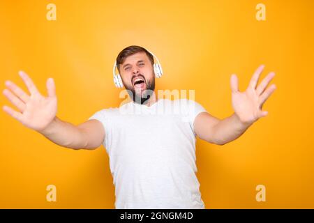 homme barbu dans un casque blanc chante fort et des gestes avec ses mains. Banque D'Images