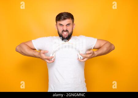 homme barbu, amoureux de musique tient des écouteurs blancs devant lui. Banque D'Images