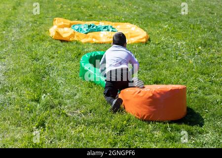 Le bébé joue dans la cour. Vacances d'été pour enfants. Un obstacle sportif pour un pré-chooler. Le garçon saute sur une douce pode sur la pelouse. Banque D'Images