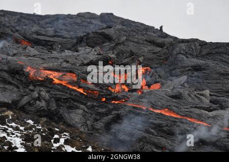 Coulée de lave à Faggadalsfjall, Islande. La croûte de lave refroidie est noire, tandis que la lave fondue est rouge et orange. Banque D'Images