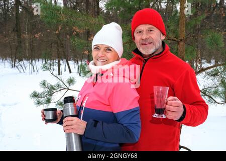 Le couple boit des boissons chaudes au parc d'hiver Banque D'Images