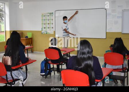 MOSQUERA, COLOMBIE - 31 août 2021 : un jeune enseignant et des élèves de sexe masculin dans la salle de classe pendant la leçon portant des masques de sécurité Banque D'Images