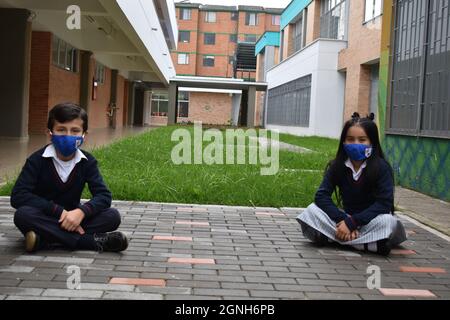 MOSQUERA, COLOMBIE - 31 août 2021 : deux jeunes étudiants assis sur le terrain sur le campus portant des masques de sécurité Banque D'Images