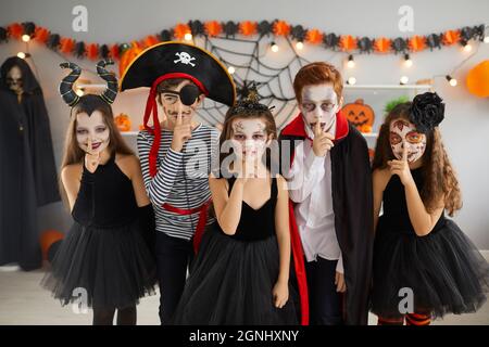 Enfants en costumes d'Halloween faisant le doigt sur le geste de lèvre pour vous faire garder leur secret effrayant Banque D'Images