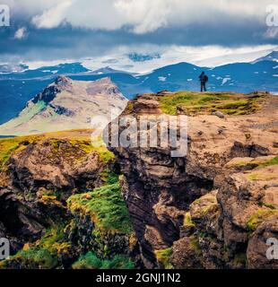 Le photographe prend des photos au bord de la falaise. Superbe vue d'été sur la réserve naturelle de Dyrholaey. Magnifique scène matinale du sud de l'Islande, en Europe. Banque D'Images