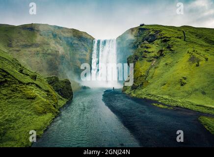 Vue depuis un drone volant. Vue spectaculaire sur la chute d'eau de Skogafoss, au soleil de minuit. Magnifique paysage d'été de la rivière Skoga, Islande, Europe. Tonne de filtre verte Banque D'Images