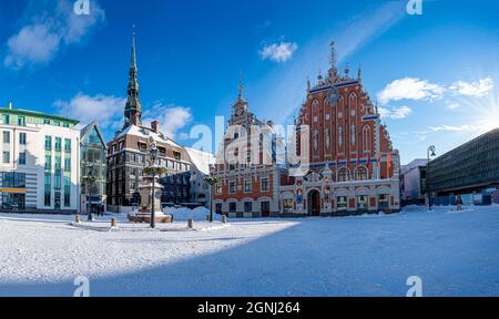 Place de l'hôtel de ville pendant la journée ensoleillée de neige en hiver à Riga, en Lettonie. Vue sur la maison enneigée des Blackheads et la statue de Roland dans la vieille ville de Riga. Banque D'Images