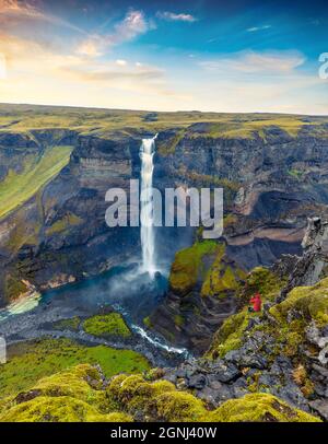 Tourist prend des photos sur le téléphone portable de la deuxième plus haute cascade d'Islande - Haifoss. Vue pittoresque au lever du soleil sur le canyon profond. Voyage en Islande. Beau Banque D'Images