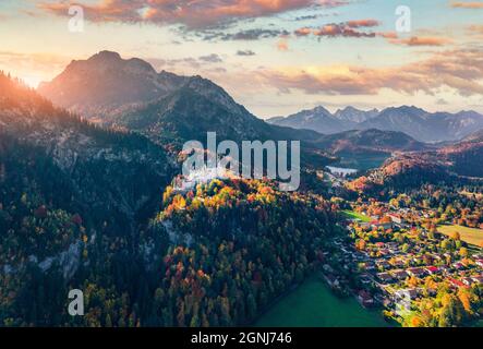 Vue depuis un drone volant. Incroyable lever de soleil d'automne sur le château de Neuschwanstein, château de conte de fées du XIXe siècle au sommet d'une colline. Une scène parfaite le matin en Bavière. C Banque D'Images