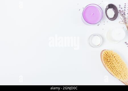 Brosse pour le corps et kit de relaxation spa avec bougies parfumées, fleurs de lavande et cosmétiques naturels sur fond blanc avec espace pour le photocopieur Banque D'Images