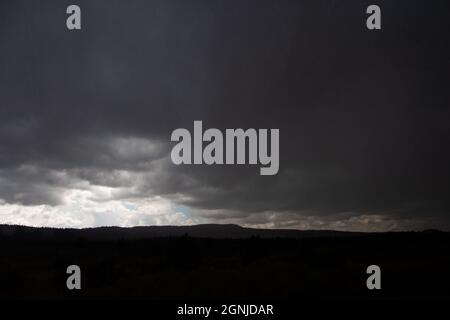 Ciel spectaculaire avec nuages de tempête au-dessus des plaines | ciel avec des nuages sombres et quelques nuages blancs et lumière du soleil sur l'horizon silhouette noire Banque D'Images