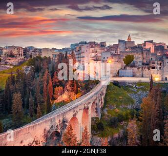 Viaduc ancien au-dessus d'un canyon profond. Lever de soleil de printemps coloré sur Gravina dans la ville de Puglia. Magnifique scène matinale d'Apulia, Italie, Europe. Concept de déplacement Banque D'Images