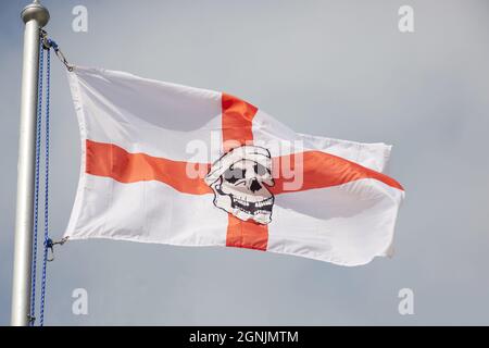 Drapeau anglais avec un visage de pirate au milieu vu volant à l'extérieur sur le sommet d'un mât. Banque D'Images