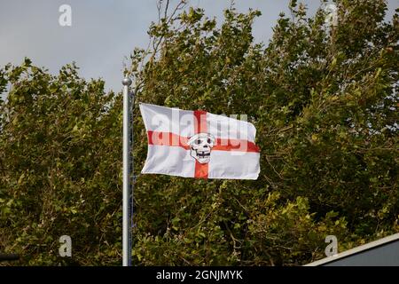Drapeau anglais avec un visage de pirate au milieu vu volant à l'extérieur sur le sommet d'un mât. Banque D'Images